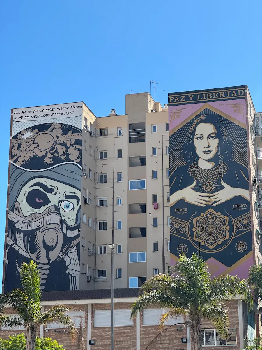 Dos murales gigantes en fachadas contiguas de Málaga, uno con una mujer y el mensaje Paz y Libertad, y otro con un astronauta estilizado