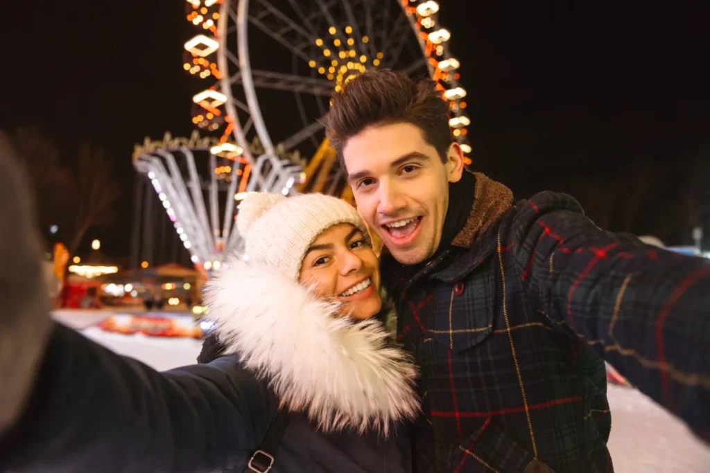 Pareja haciéndose un selfie en una pista de hielo iluminada por la noche
