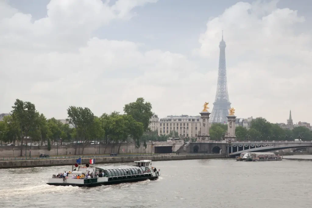 Barco navegando por el Sena junto al puente Alexandre III y la Torre Eiffel